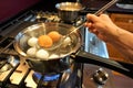 Brown eggs being removed from boiling water on gas stove Royalty Free Stock Photo