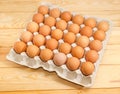 Brown eggs in the cardboard egg tray on wooden surface Royalty Free Stock Photo