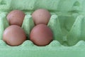4 brown eggs in green packaging. Packging is made of recycled matherials