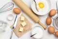 Brown eggs on metal stand. Butter and knife on paper. Egg yolk with flour and spoon in bowl. Milk in bowl and rolling pin on table Royalty Free Stock Photo