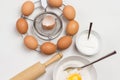 Brown eggs on metal stand. Egg yolk with flour and spoon in bowl. Milk in bowl and rolling pin on table Royalty Free Stock Photo