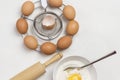 Brown eggs on metal stand. Egg yolk with flour and spoon in bowl. Milk in bowl and rolling pin on table Royalty Free Stock Photo