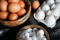 Brown eggs in a wooden bowl, white chicken eggs in a tray next to quail eggs and feathers Royalty Free Stock Photo