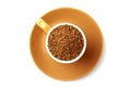 Brown elegant cup full of instant coffee granules, saucer under it. View from above, so it makes perfect round shape.