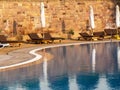 Brown empty sunbeds near the swimming pool with closed umbrellas at the sunrise Royalty Free Stock Photo