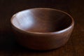Brown empty wooden bowl on dark wood. Royalty Free Stock Photo