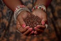 Brown feminine hands in traditional jewelery hold a handful of coffee