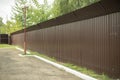 A brown fence encloses the enclosed area. Metal fence along the parking lot