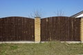 Brown fence of wooden planks and bricks in the green grass against the blue sky Royalty Free Stock Photo