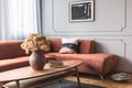 Brown flowers in pottery vase on stylish coffee table in chic living room interior with black and white poster on the grey wall