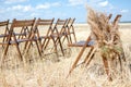 Brown folding chairs decorated with pampas. The wedding ceremony is in an open field in a rustic style. Seats for guests Royalty Free Stock Photo
