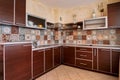 Brown furniture in the kitchen with mosaic colorful tiles on the walls