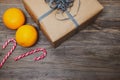 Saint Nicholas concept with brown gift box, oranges and striped candy canes on wooden background. Royalty Free Stock Photo