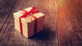 Brown gift box and red ribbon with tag on wood background with s Royalty Free Stock Photo