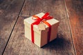 Brown gift box and red ribbon with tag on wood background with s Royalty Free Stock Photo