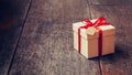 Brown gift box and red ribbon with tag on wood background with s Royalty Free Stock Photo