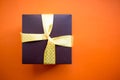 Brown gift box with yellow ribbon on orange background. Top view with copy space. Royalty Free Stock Photo