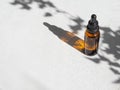 Brown glass with a dropper. Bottle mockup cosmetic oil dropper on a grey background and shadows of plants. Copy space