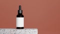 Brown glass serum bottle on marble podium with pink background