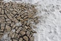 Brown granite paving of irregular stones. Frozen partially snow covered country road courtyard at the entrance to the building. Re Royalty Free Stock Photo