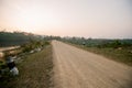 Brown gravel road In a rural area in Thailand There is a kilometer pole. In the back and with mountains During the time when the Royalty Free Stock Photo