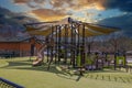 A brown and green jungle gym in the park with a yellow trap roof surrounded by green Astroturf, buildings, parked cars Royalty Free Stock Photo