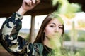 Brown hair girl holds a smoke bomb that throws yellow smoke around. Young girl wears an urban style, military jacket and piercing