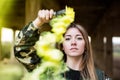 Brown hair girl holds a smoke bomb that throws yellow smoke around. Young girl wears an urban style, military jacket and piercing