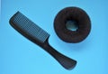 Brown hair roller and black plastic comb on a blue background Royalty Free Stock Photo