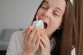 Brown haired beautiful woman biting appetizing piece of cake with cream has sweet tooth feeling temptation to eat delicious