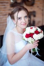 Brown-haired bride with classic wedding hairstyle, smiling taking wedding bouquet in her hands.
