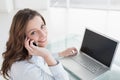 Brown haired businesswoman using laptop and cellphone in office Royalty Free Stock Photo