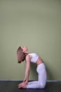 Brown-haired Caucasian young woman doing stretching exercise camel pose or ushtrasana.