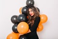 Brown-haired girl in stylish dress posing with halloween balloons. Debonair attractive woman standing on white