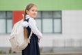 Brown-haired schoolgirl holding book enjoys attending school