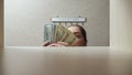 Brown-haired woman takes money banknotes from wooden shelf