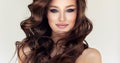 Brown haired woman with voluminous, shiny and curly hairstyle.Tender look to the eyes of viewer. Hairstyling art.