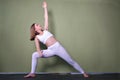 Brown-haired woman wearing black sportswear practicing yoga, doing Utthita parsvakonasana exercise on mat, standing in Extended