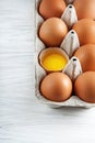 Brown hen`s eggs one egg yolk visible decorated in a box Royalty Free Stock Photo