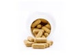 Brown herbal supplement capsules pour out from white opened plastic bottle Royalty Free Stock Photo