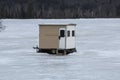 Brown ice fishing shelter sits on ice, Errol, New Hampshire.