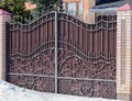 Brown iron gate with forgery pattern and brick columns in sunlight Royalty Free Stock Photo
