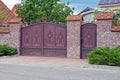 A brown iron gate and a wrought iron door and part of a stone fence