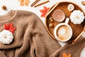 Brown knitted sweater, cup of coffee, maple leaves, pumpkins on white background. Autumn, fall flat lay composition