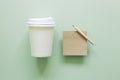 Brown kraft memo pad, pencil, paper coffee cup on green background Royalty Free Stock Photo