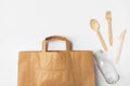 Brown Kraft paper grocery shopping bag wooden flatware cutlery on white background. Plastic-free alternatives zero waste