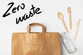 Brown Kraft paper grocery shopping bag wooden flatware cutlery on white background. Plastic-free alternatives zero waste