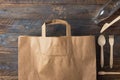 Brown kraft paper grocery shopping bag wooden flatware on wood background. Plastic-free alternatives zero waste Royalty Free Stock Photo