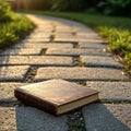 A brown, leather-bound book rests on a sunlit stone path. The pathway consists of Royalty Free Stock Photo