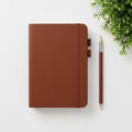 Brown leather-bound notebook with an elastic strap lies on a white surface. A matching brown pencil Royalty Free Stock Photo
